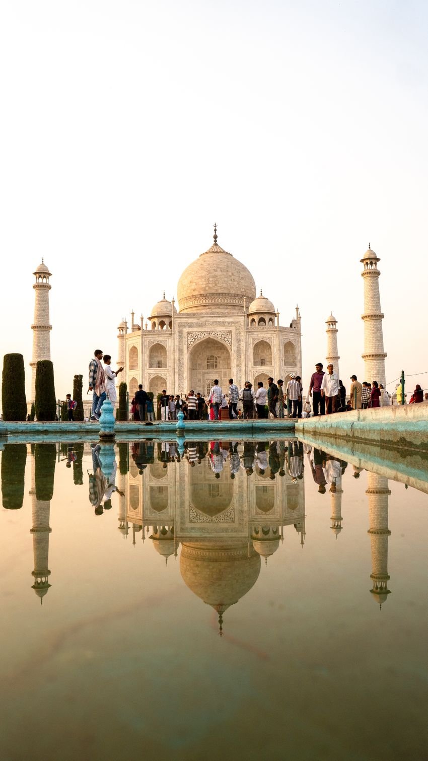 Taj Mahal et visiteurs près du bassin, dans une lumière matinale, avec le reflet du monument